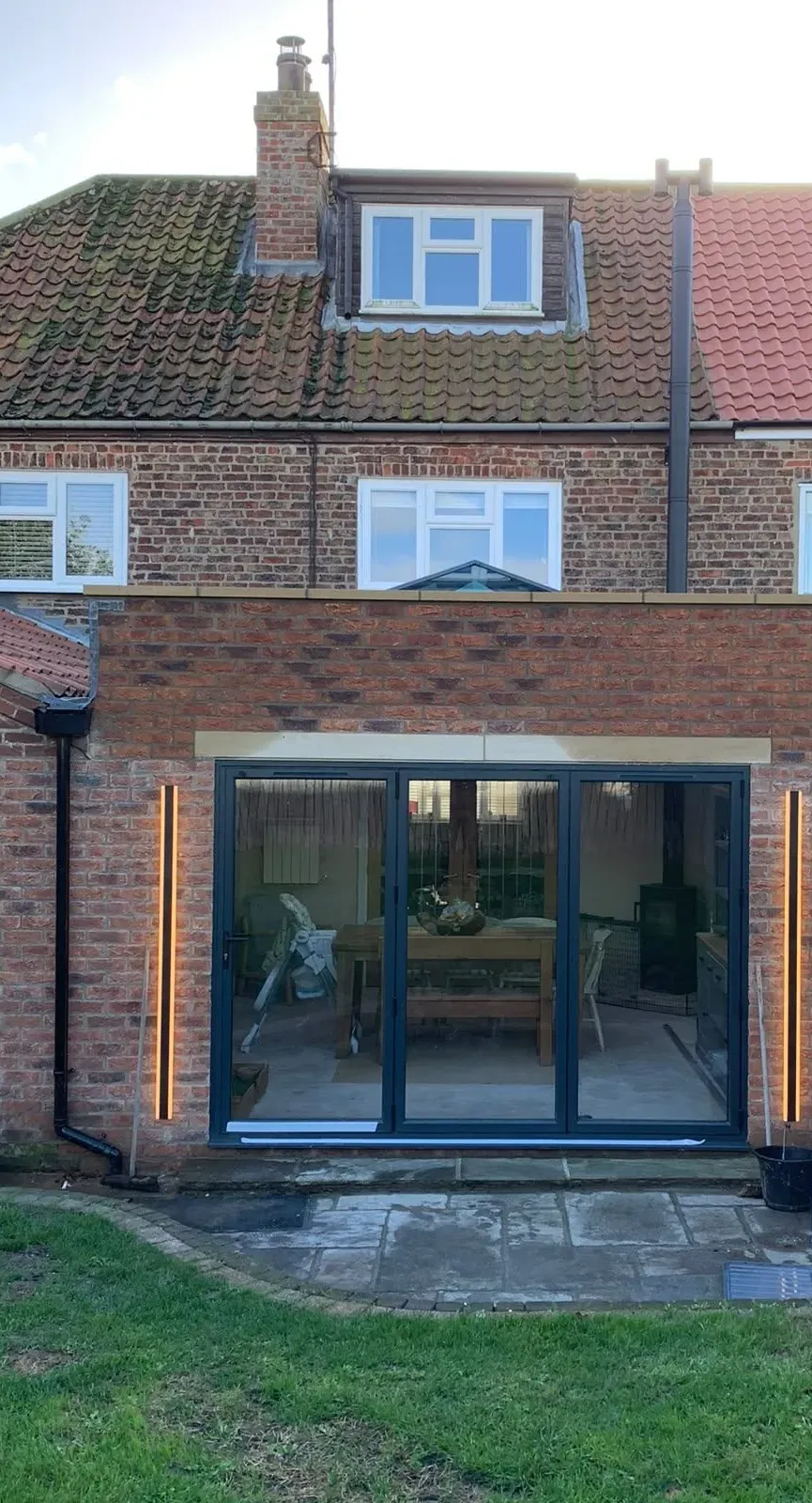 Brick rear extension with grey bi-fold doors and wall lights