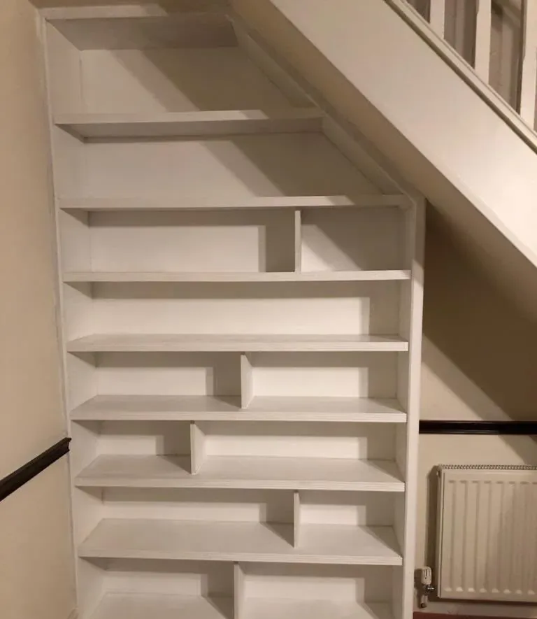 Bespoke white understairs shelving unit fitted beneath a staircase
